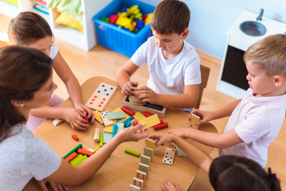 Preschool teacher with children playing with didactic toys